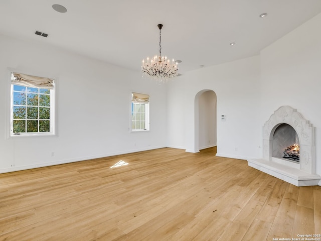 unfurnished living room featuring a premium fireplace, a chandelier, and light hardwood / wood-style floors