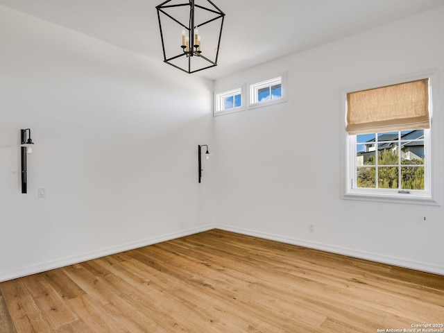 unfurnished room featuring a chandelier and light hardwood / wood-style floors