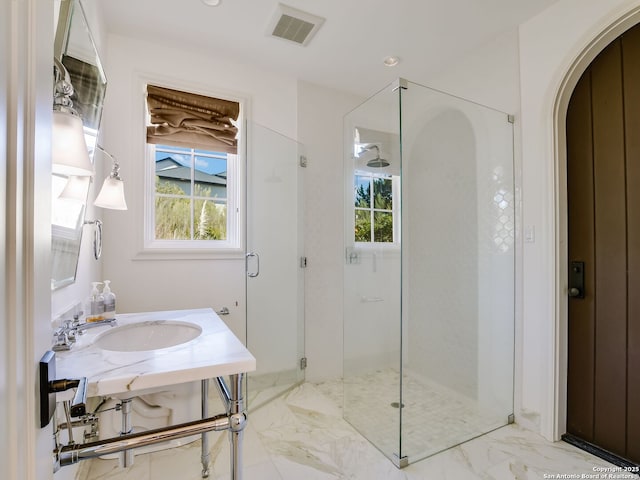 bathroom with a shower with shower door, sink, and a wealth of natural light