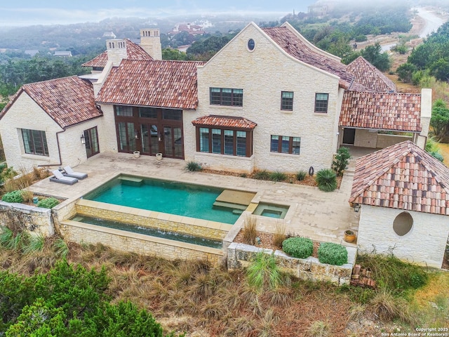 exterior space with french doors, an in ground hot tub, and a patio