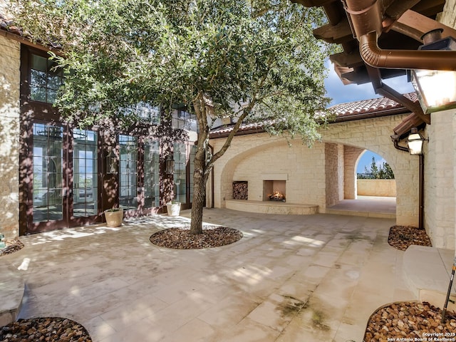 exterior space with french doors and an outdoor stone fireplace