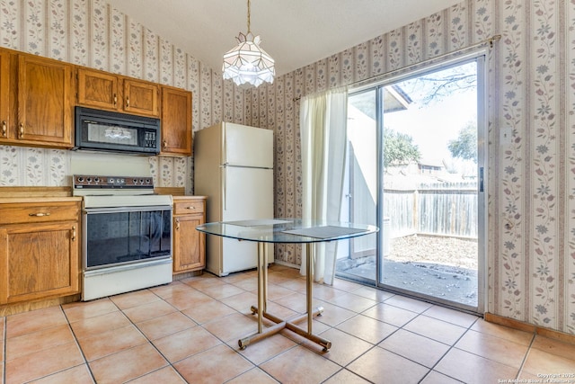 kitchen featuring light tile patterned flooring, vaulted ceiling, white appliances, and decorative light fixtures