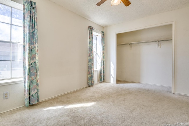 unfurnished bedroom with a closet, light carpet, multiple windows, and a textured ceiling