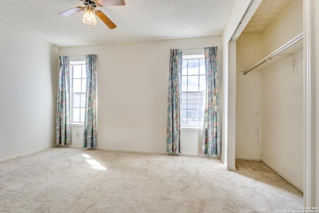 unfurnished bedroom featuring multiple windows, a textured ceiling, and carpet flooring