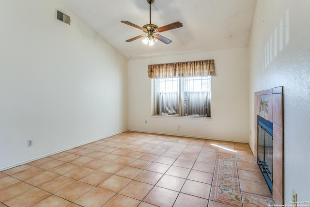 tiled empty room with high vaulted ceiling, a tile fireplace, and ceiling fan