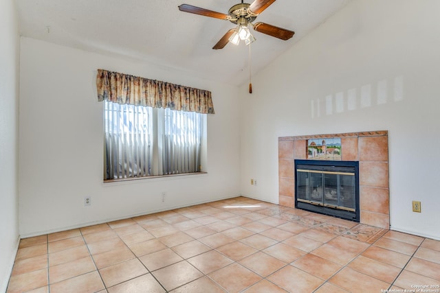 unfurnished living room with a tiled fireplace, light tile patterned floors, lofted ceiling, and ceiling fan