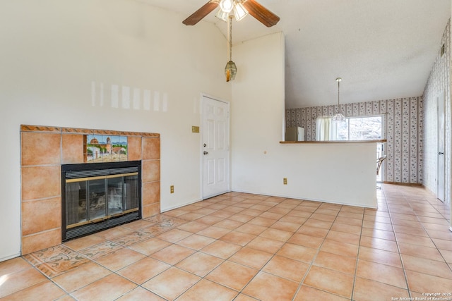 unfurnished living room with lofted ceiling, light tile patterned floors, a tile fireplace, and ceiling fan