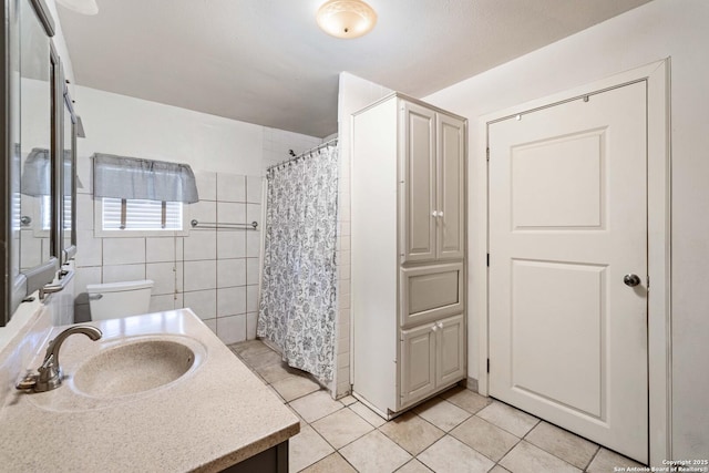 bathroom featuring walk in shower, tile patterned floors, toilet, tile walls, and vanity