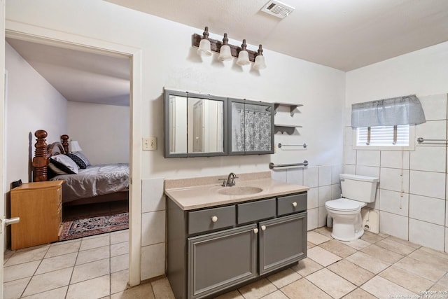 bathroom with tile patterned floors, toilet, vanity, and tile walls