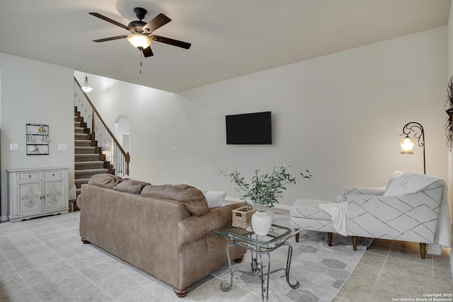 living room with arched walkways, stairs, a ceiling fan, and baseboards