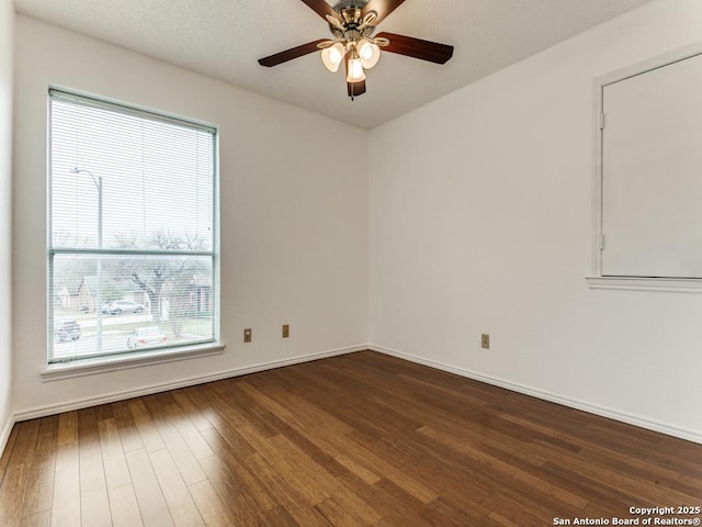 empty room with ceiling fan and dark hardwood / wood-style flooring