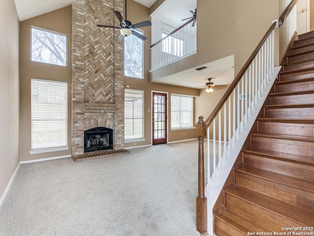 unfurnished living room with ceiling fan, lofted ceiling, a fireplace, and light carpet