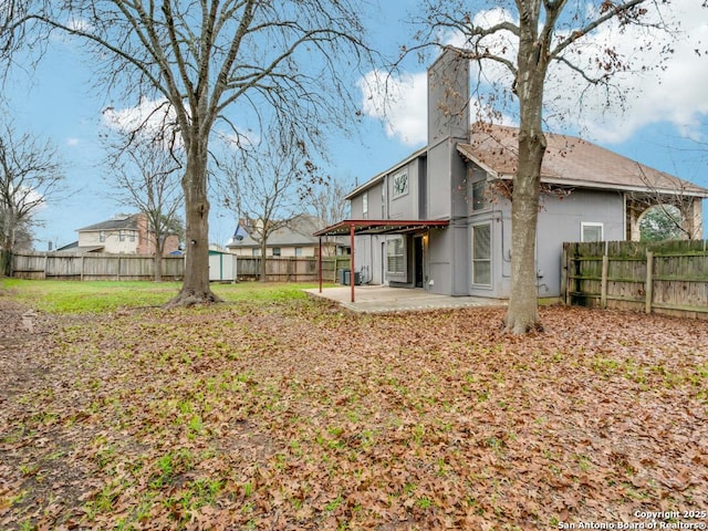 back of house with a storage unit and a patio area