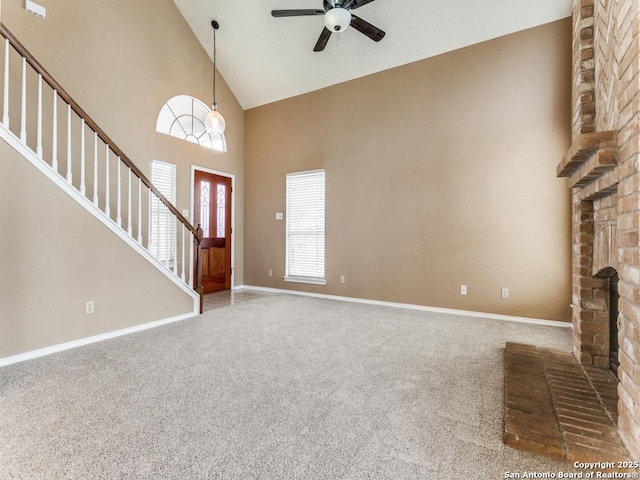 unfurnished living room featuring a brick fireplace, high vaulted ceiling, ceiling fan, and carpet