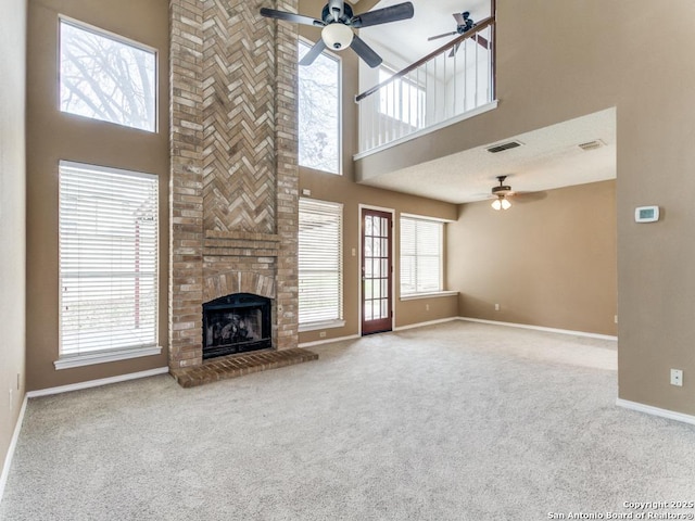 unfurnished living room featuring ceiling fan, carpet flooring, a fireplace, and a wealth of natural light