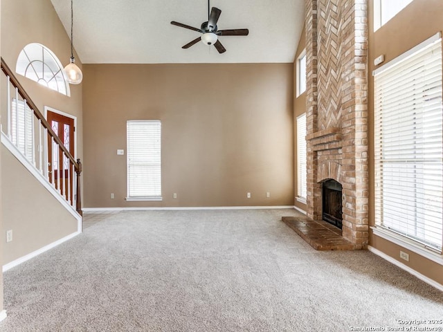 unfurnished living room featuring a brick fireplace, plenty of natural light, high vaulted ceiling, and carpet