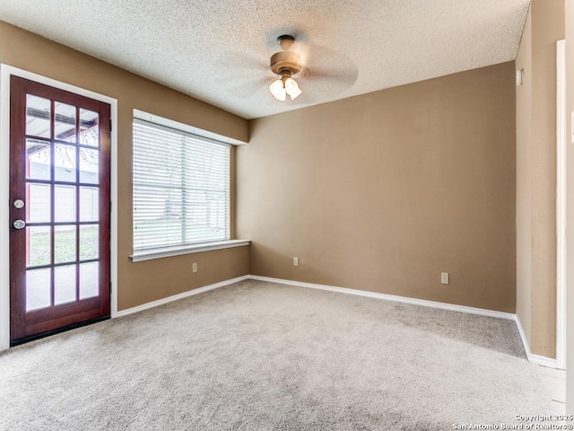 carpeted empty room featuring a textured ceiling and ceiling fan