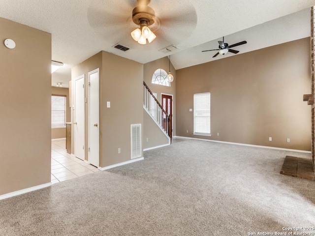 unfurnished living room with ceiling fan, a healthy amount of sunlight, light carpet, and a textured ceiling