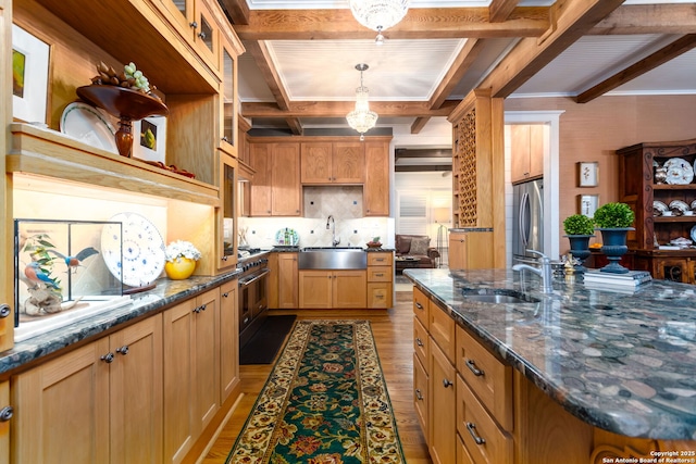 kitchen with appliances with stainless steel finishes, sink, hanging light fixtures, and light hardwood / wood-style flooring