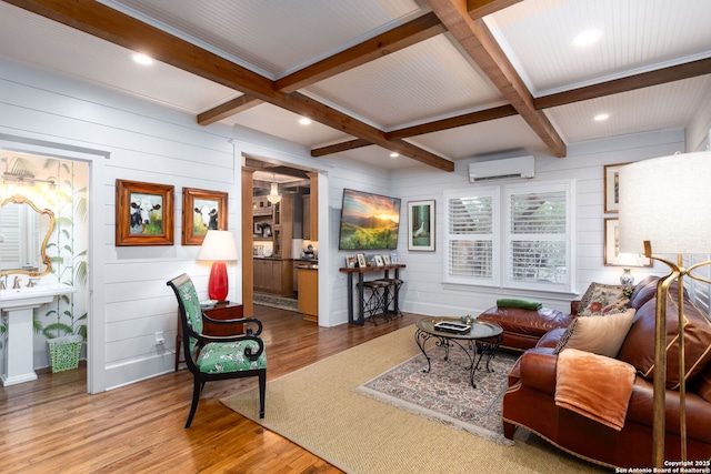 living room featuring coffered ceiling, wood-type flooring, an AC wall unit, and beamed ceiling