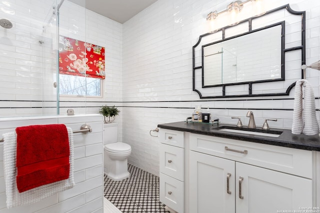 bathroom featuring tile walls, vanity, an enclosed shower, toilet, and tile patterned floors