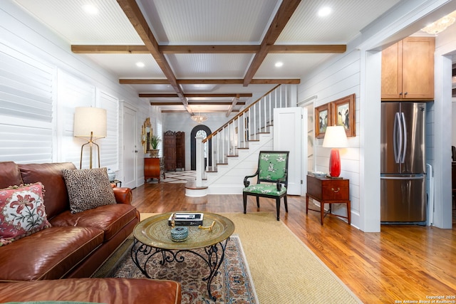 living room with beamed ceiling, coffered ceiling, and light hardwood / wood-style flooring