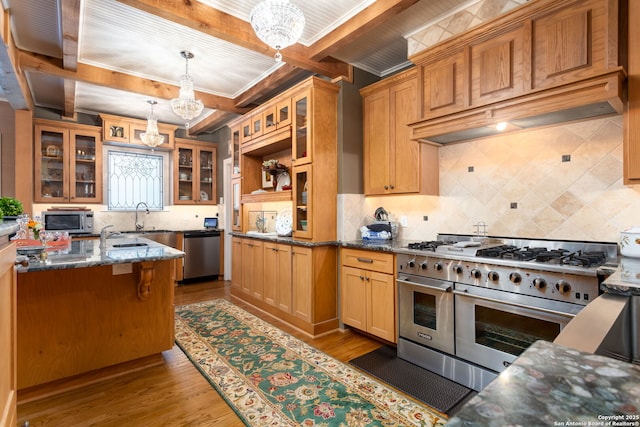 kitchen with stainless steel appliances, hanging light fixtures, dark stone countertops, and an inviting chandelier