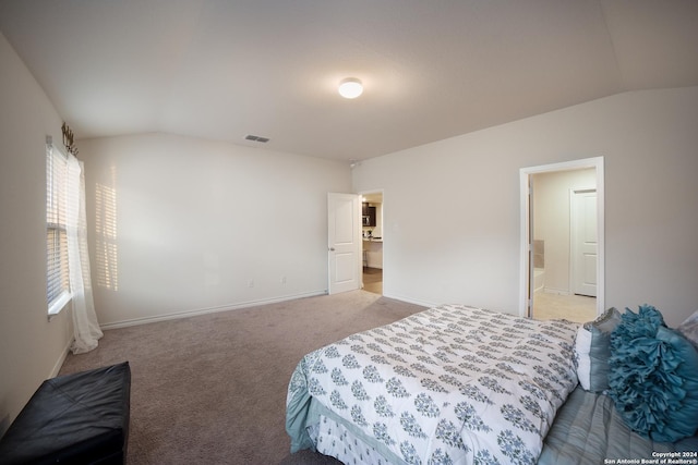 carpeted bedroom featuring ensuite bath and vaulted ceiling