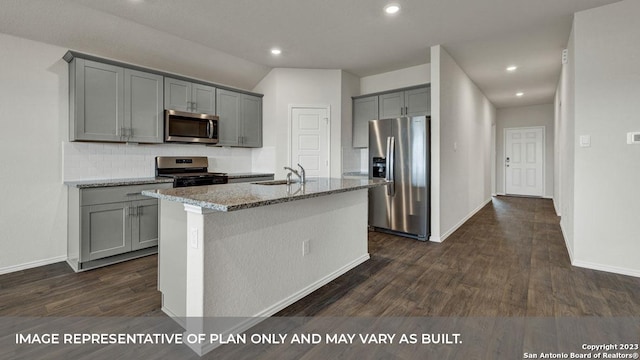 kitchen with sink, gray cabinetry, appliances with stainless steel finishes, an island with sink, and light stone countertops