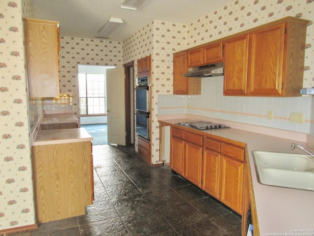 kitchen featuring double oven, stainless steel gas cooktop, sink, and tasteful backsplash