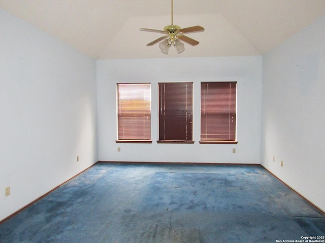 spare room with dark carpet, vaulted ceiling, and ceiling fan