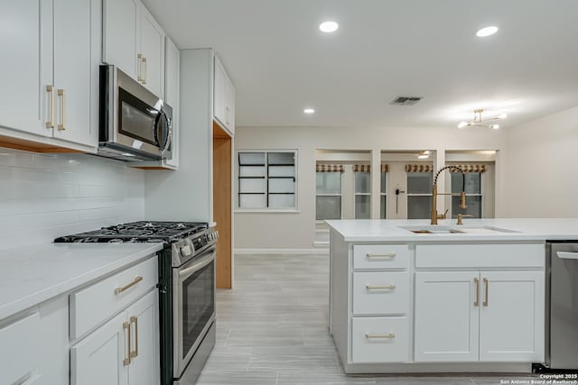 kitchen featuring sink, white cabinetry, backsplash, stainless steel appliances, and light stone counters