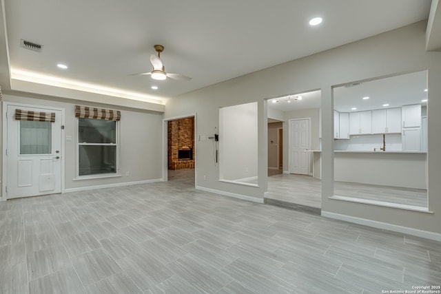 unfurnished living room with a brick fireplace and ceiling fan