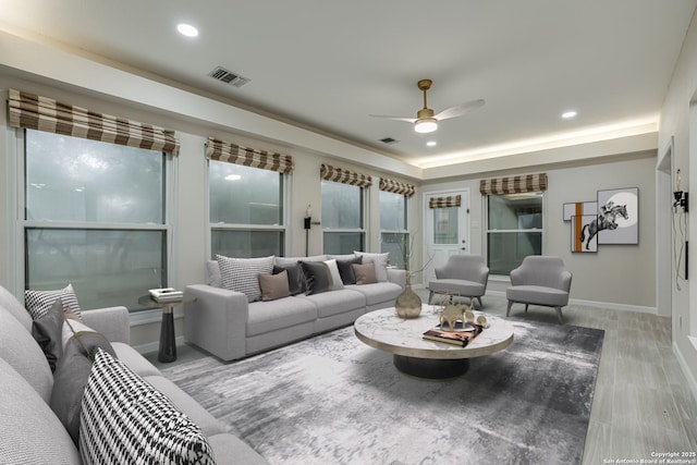 living room featuring a raised ceiling, wood-type flooring, and ceiling fan