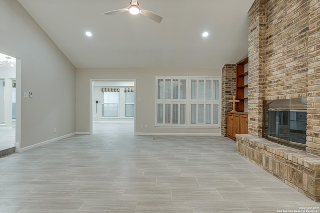 unfurnished living room featuring vaulted ceiling, a brick fireplace, and ceiling fan