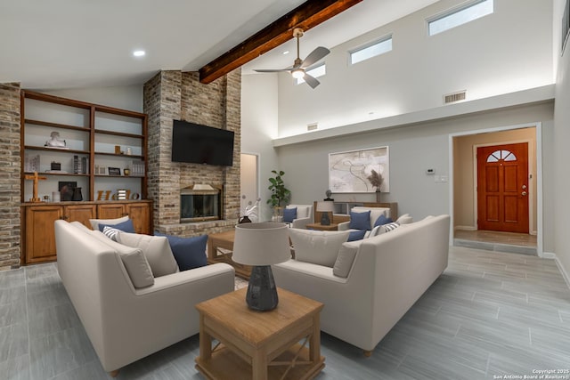 living room with beamed ceiling, ceiling fan, a brick fireplace, and high vaulted ceiling