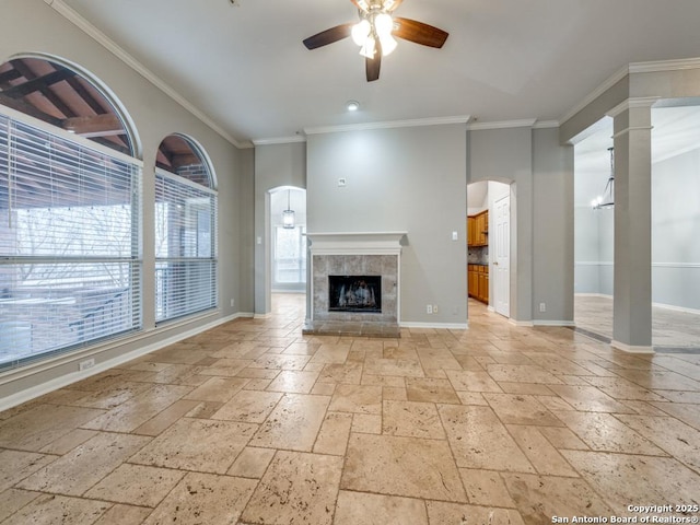 unfurnished living room featuring ornate columns, ornamental molding, ceiling fan, and a fireplace