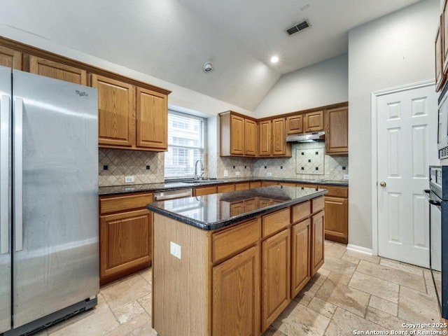 kitchen featuring sink, vaulted ceiling, dark stone countertops, appliances with stainless steel finishes, and a kitchen island