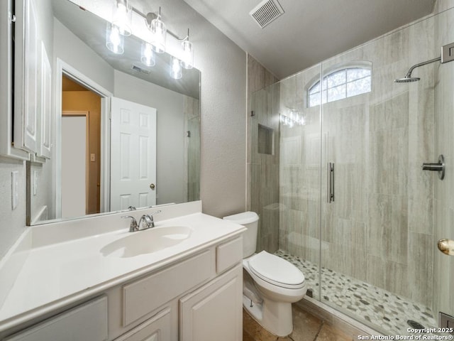 bathroom with vanity, a shower with door, and toilet