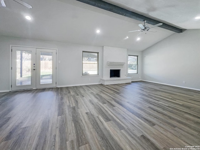 unfurnished living room with dark wood-type flooring, ceiling fan, a fireplace, lofted ceiling with beams, and french doors