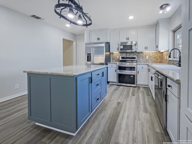 kitchen with stainless steel appliances, sink, white cabinets, and decorative light fixtures