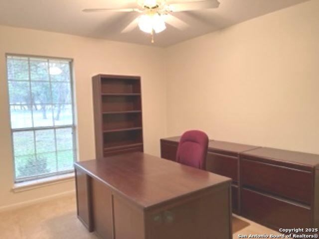 carpeted home office featuring ceiling fan