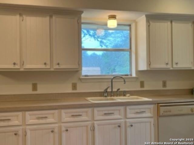 kitchen featuring dishwasher, sink, and white cabinets