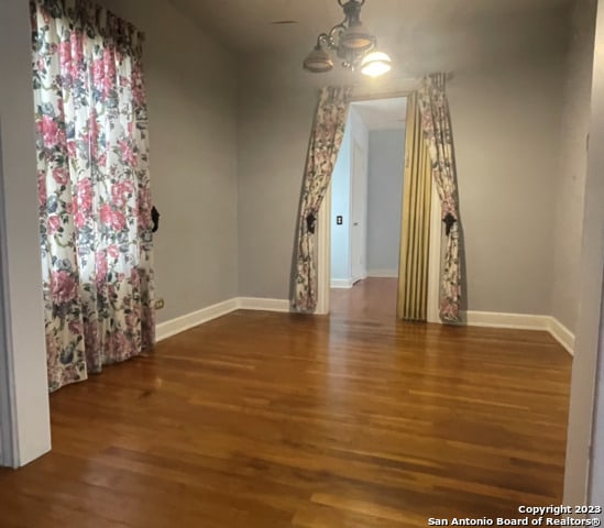 empty room featuring an inviting chandelier and dark hardwood / wood-style floors