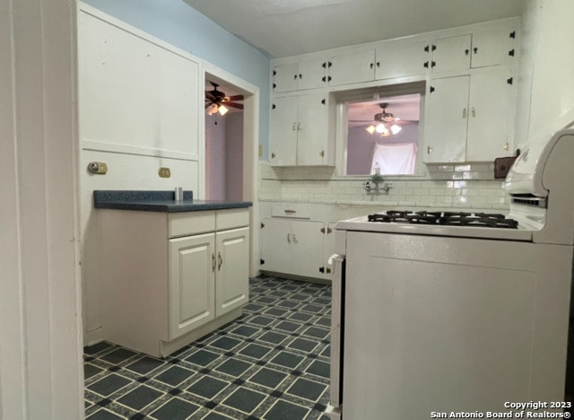 kitchen featuring white cabinetry, white gas range oven, ceiling fan, and decorative backsplash