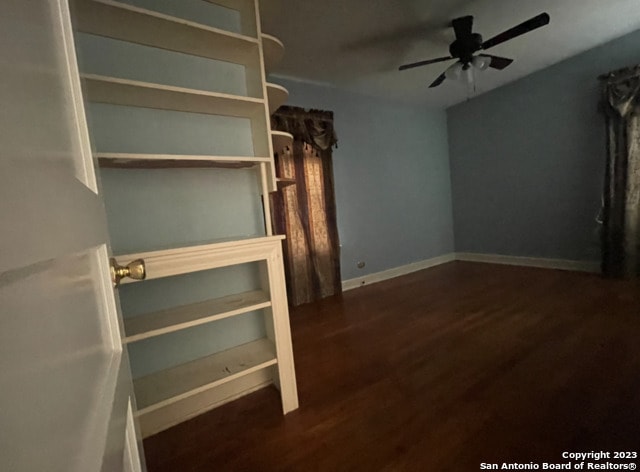 unfurnished living room featuring dark wood-type flooring and ceiling fan