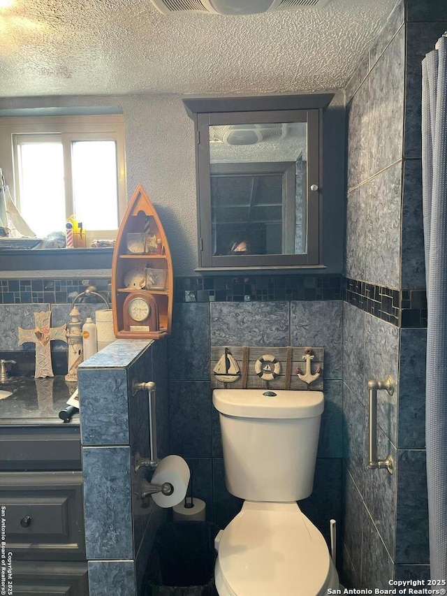 bathroom featuring tile walls, a textured ceiling, and toilet