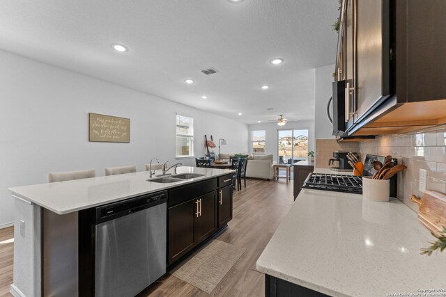 kitchen featuring appliances with stainless steel finishes, sink, a center island with sink, and light hardwood / wood-style flooring