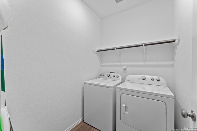 clothes washing area with separate washer and dryer and dark hardwood / wood-style floors