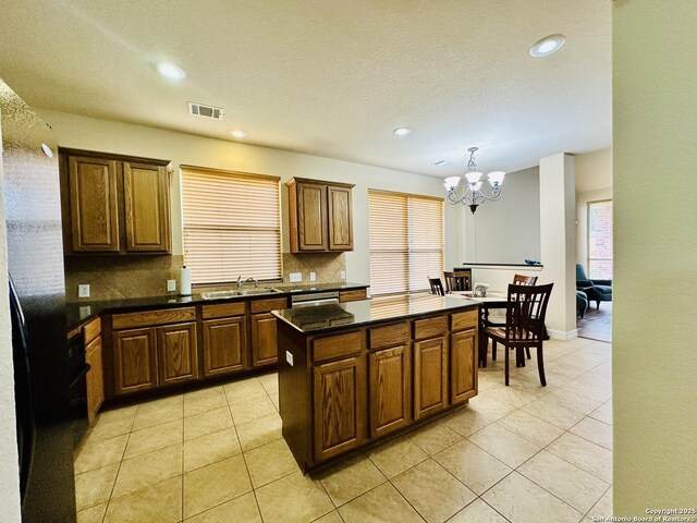 kitchen featuring sink, a chandelier, a kitchen island, pendant lighting, and backsplash